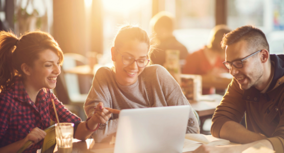 Three people studying gathering around a laptop computer